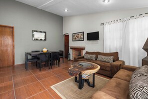 Una sala de estar con sofá, mesa de centro, chimenea, televisión y un comedor con sillas y mesa.