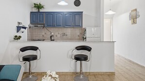 Una cocina moderna con dos taburetes de bar, un reloj y una planta en la encimera.