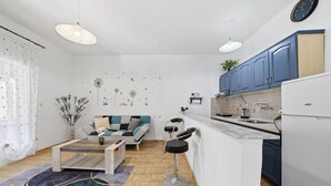 Una cocina moderna con armarios azules, un refrigerador blanco y una zona de comedor con sofá y taburetes de bar.