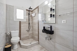 Een moderne badkamer met douche, toilet en wastafel.