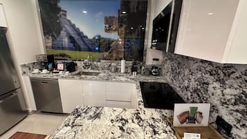 Una cocina moderna con una isla grande, electrodomésticos integrados y un mural de una pirámide.