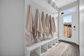 A hallway with a white bench and a row of beige towels hanging on the wall. - Calgary Urban Lodge: Hot Tub, Sauna, Game Room (Calgary)