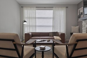 A modern living room with a brown leather sofa, two armchairs, a coffee table, and a floor lamp.