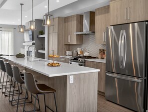 Una cocina moderna con una isla central, electrodomésticos de acero inoxidable y armarios de madera.