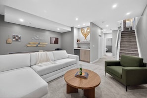 A modern living room with a sectional sofa, a round coffee table, and a green armchair.