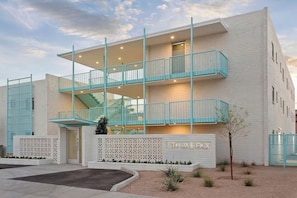 Un edificio de varios pisos con un balcón, una escalera y un letrero que dice '5TH AVE PHX'.