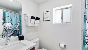Une salle de bain avec un lavabo, des toilettes et un rideau de douche.