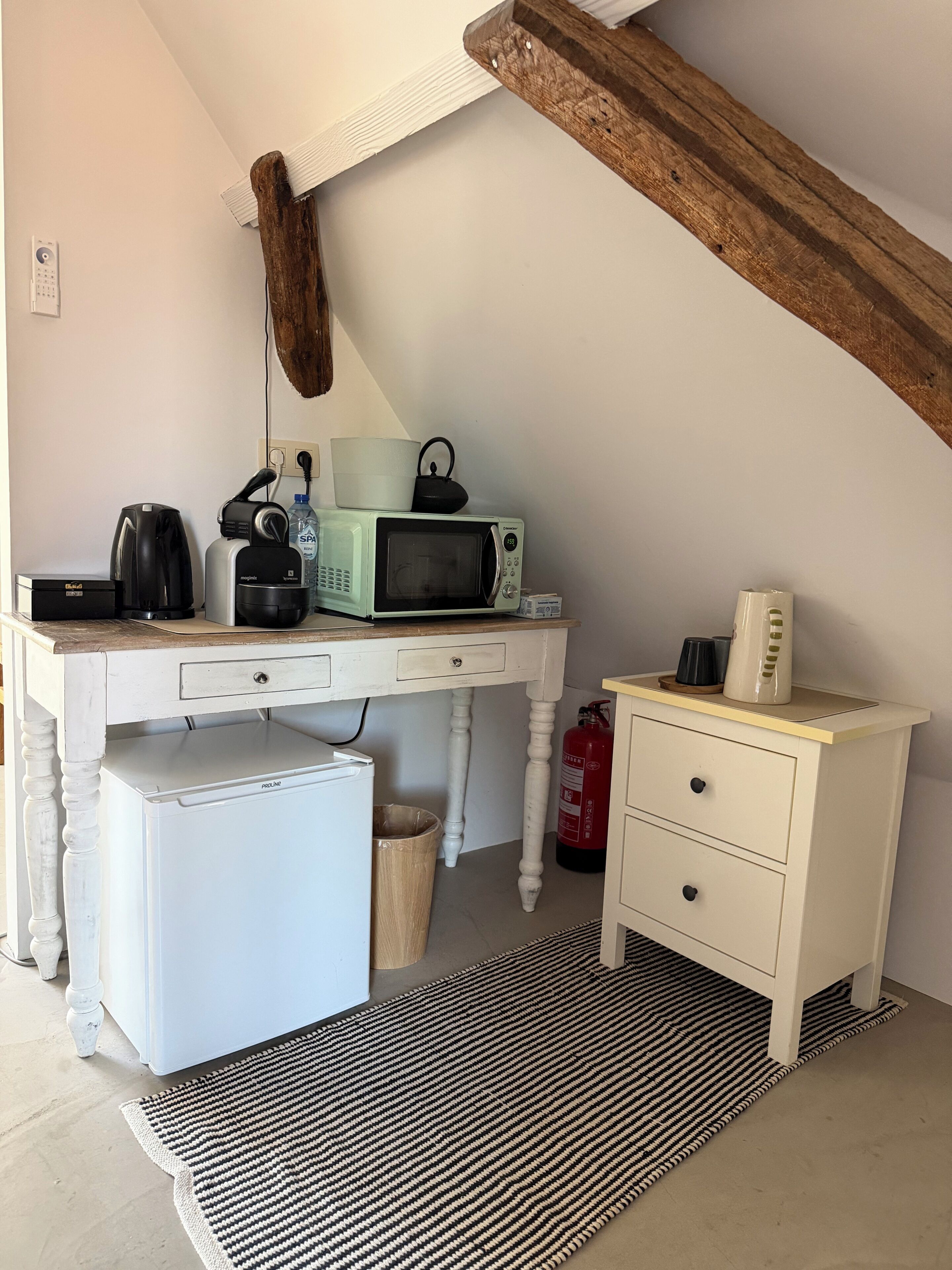 A compact kitchenette with a microwave, coffee maker, and toaster.