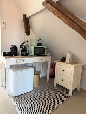 Ett litet, praktiskt kök med mikrovågsugn, kaffebryggare och brödrost.