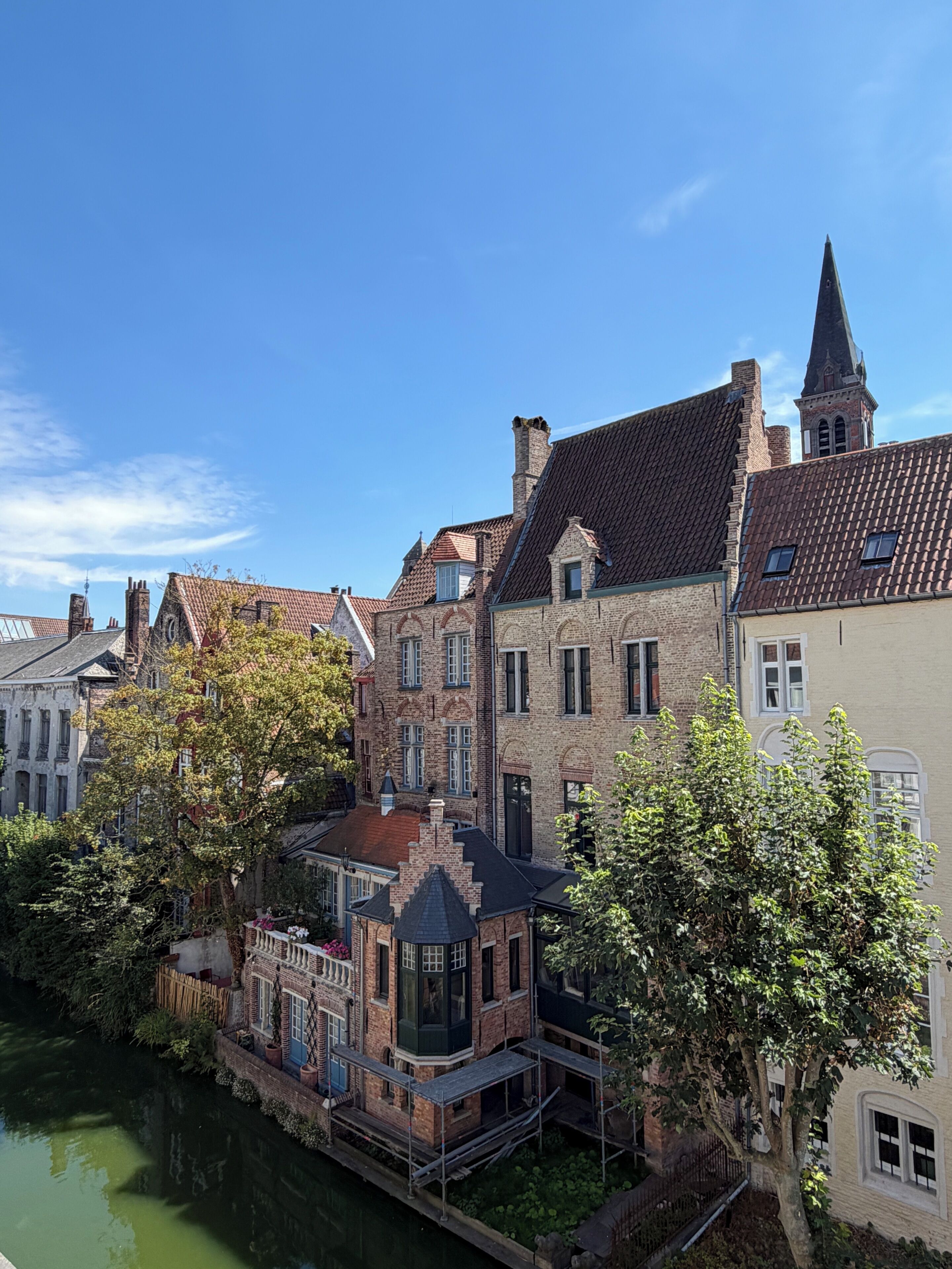 A canal-side building with a traditional brick facade, a prominent tower, and a small dock area.