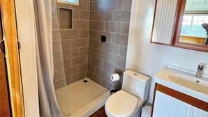 Ein Badezimmer mit Dusche, Toilette, Waschbecken und einem Fenster mit Blick.