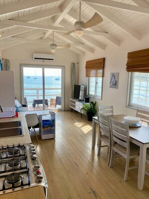 Ein geräumiges Zimmer mit einer Küche, einem Essbereich und einem großen Fenster mit Meerblick.