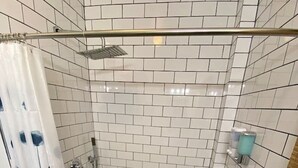 Eine Dusche mit weißen Fliesen und einer Duschbrause.