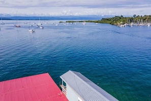 Un port de plaisance avec des bateaux, un bâtiment au toit rouge et une vue dégagée sur l’eau.