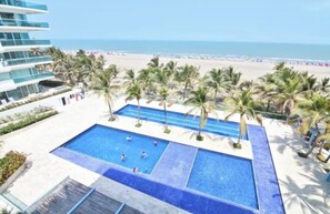 A pool area with multiple swimming pools, palm trees, and a beach view. - 🏖️MORROS 922 VACATION RENTAL, CARTAGENA DE INDIAS, COLOMBIA 🇨🇴🏝️ (La Boquilla)