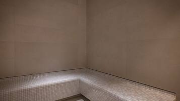 A corner of a room with tiled walls and a bench.