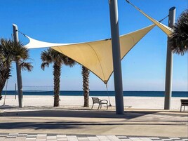Un paseo marítimo con palmeras, un banco y vista al mar.
