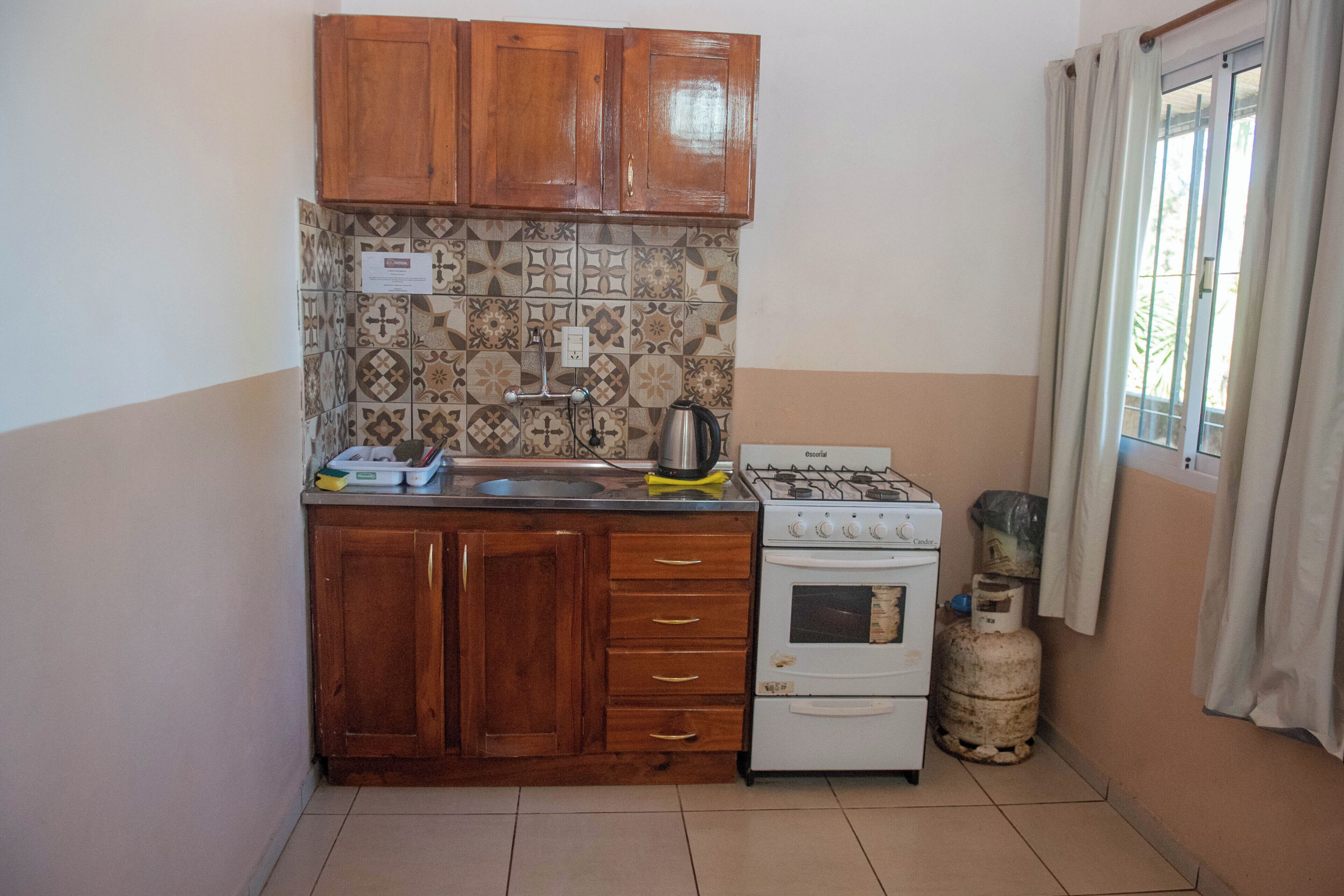 A compact kitchen with wooden cabinets, a gas stove, and a tiled backsplash.