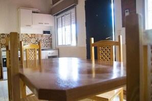 Una cocina con salpicadero de azulejos, una ventana y una mesa de comedor de madera con sillas.