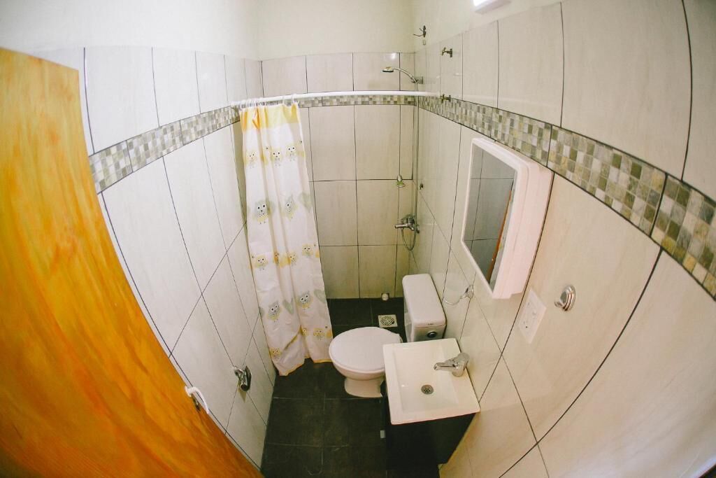 A small bathroom with a toilet, sink, and shower.