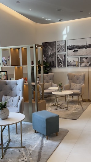 A modern interior with a sofa, ottoman, and two chairs, a coffee table, and a decorative partition with shelves. - 1BR Suite | Marriott Dubai | Separate Living Area, Full Kitchen, Metro Walk (Dubai)