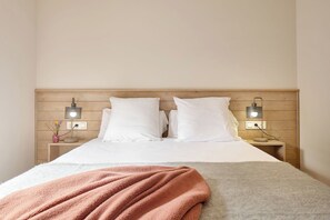 A bed with white linens, a pink blanket, and two bedside lamps. - Aiguamog  by FeelFree Rentals (Naut Aran)