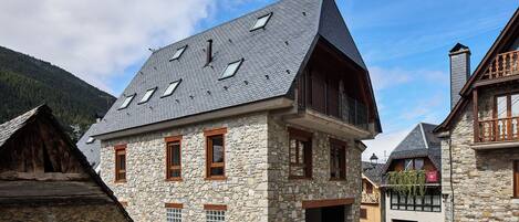 A stone building with multiple windows and a sloped roof.