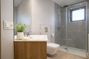 Ein modernes Badezimmer mit einer Duschkabine aus Glas, einem Holzausleger und einem Blumentopf.