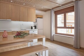 Eine moderne Küche mit Holzschränken, einer weißen Arbeitsplatte und einem Fenster mit Vorhängen.
