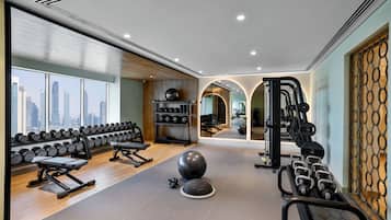 Une salle de sport équipée de matériel d’exercice, dotée d’un mur avec des miroirs et offrant une vue sur la ville.
