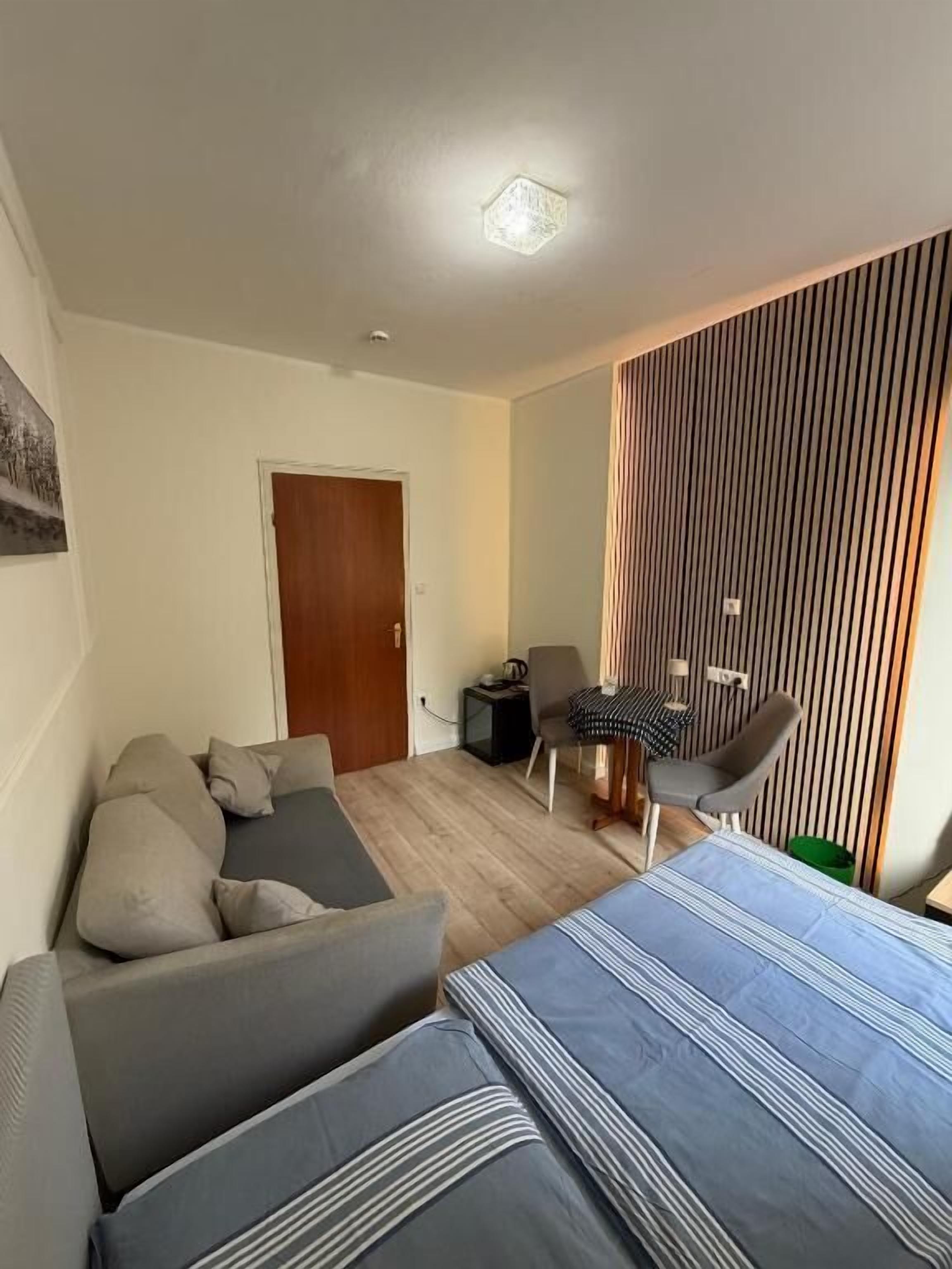 Quarto de hotel moderno com sofá, cama com roupa de cama listrada, escrivaninha com cadeira e cortina listrada.