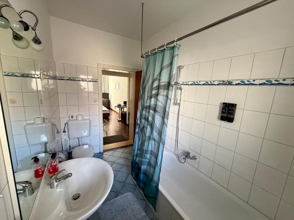 Un bagno con lavandino, specchio, doccia e WC.