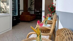 A balcony with wicker chairs, a glass table, and a view of the building's interior. - Hotel Runge 24-7 check in & free parking (Kiel)