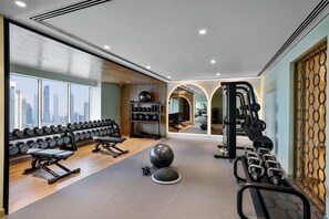 Un gimnasio con equipo de ejercicio, un espejo grande y vistas a la ciudad.