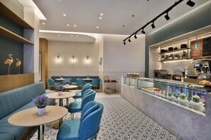 Ein modernes Restaurant mit blauen Sitzplätzen, einer Theke mit Speisekarte und einer Wanddekoration mit Flamingos.