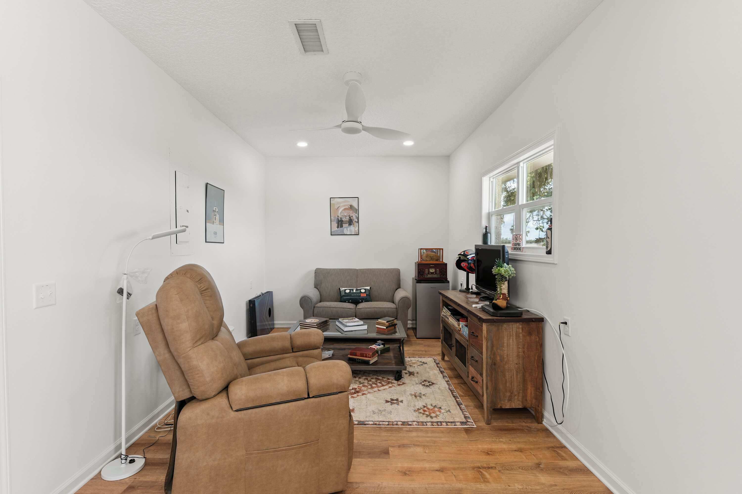 A living room with a sofa, armchair, coffee table, and a TV stand.