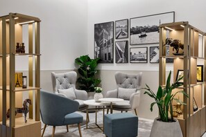 A modern room with two armchairs, a round table, and a bookshelf with decorative items. - Marriott Dubai | Premium 1BR | Apt-styled Comfort on Sheikh Zayed Rd | 2 Units (Dubai)