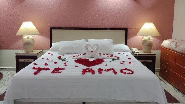 A hotel room with a bed, two bedside lamps, a telephone, and a red wall. - HOTEL TAMAZUNCHALE (Tamazunchale)