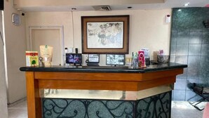 A reception desk with a framed picture above it, a door in the background, and a tiled wall to the right. - HOTEL TAMAZUNCHALE (Tamazunchale)