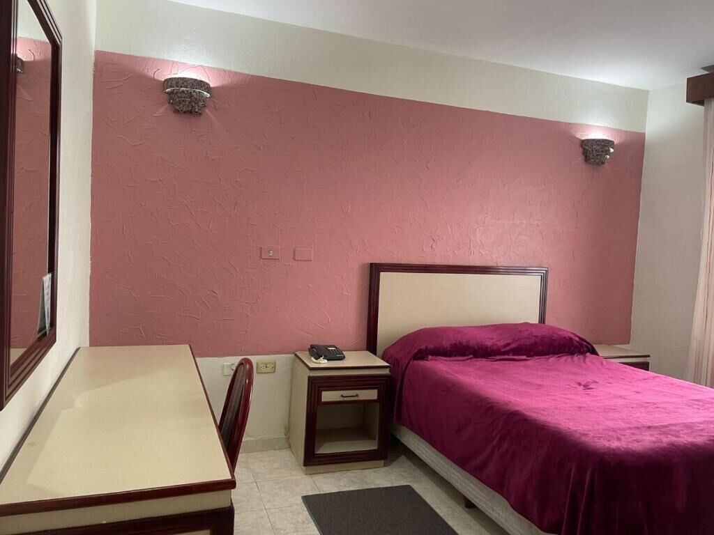 Un dormitorio con cama, mesita de noche y escritorio.