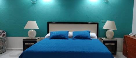 Une chambre à coucher comprenant un lit, deux tables de chevet avec des lampes, une table de nuit et une commode.
