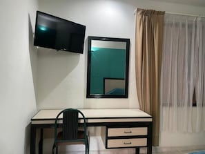 A room with a desk, a chair, a television mounted on the wall, a mirror, and a window with curtains. - HOTEL TAMAZUNCHALE (Tamazunchale)