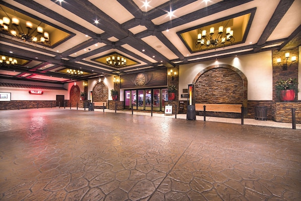 A spacious lobby with a stone floor, wooden beams, and a large chandelier.