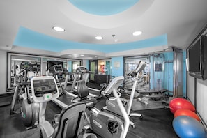 A gym with treadmills, elliptical machines, and exercise balls.