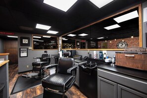 Un salon de coiffure équipé d’un miroir, d’un fauteuil de barbier et de divers outils de soins.