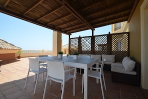 Eine Terrasss mit Tisch, Stühlen, einer Couch und einem Holzzimmerfenster.