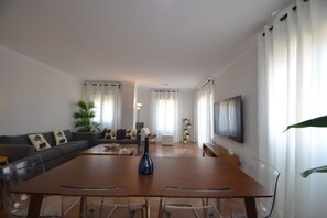 Ein modernes Wohnzimmer mit Esstisch, Sofa und Fernseher.