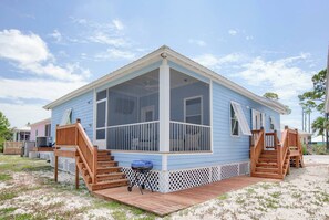 Ein eingeschossiges Haus mit einer Veranda, einer kleinen Terrasse und einem Moskitonetz-Bereich.