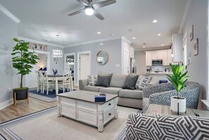 Ein modernes Wohnzimmer mit Essbereich, Küche, Deckenventilator und Topfpflanzen.