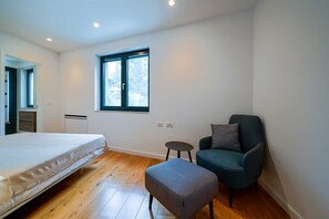 Ein Schlafzimmer mit Bett, Fenster, Stuhl und kleinem Tisch.